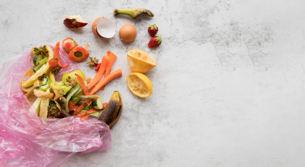 A collection of fruit and vegetable scraps, eggshells, and discarded food items in a pink bag on a gray surface.